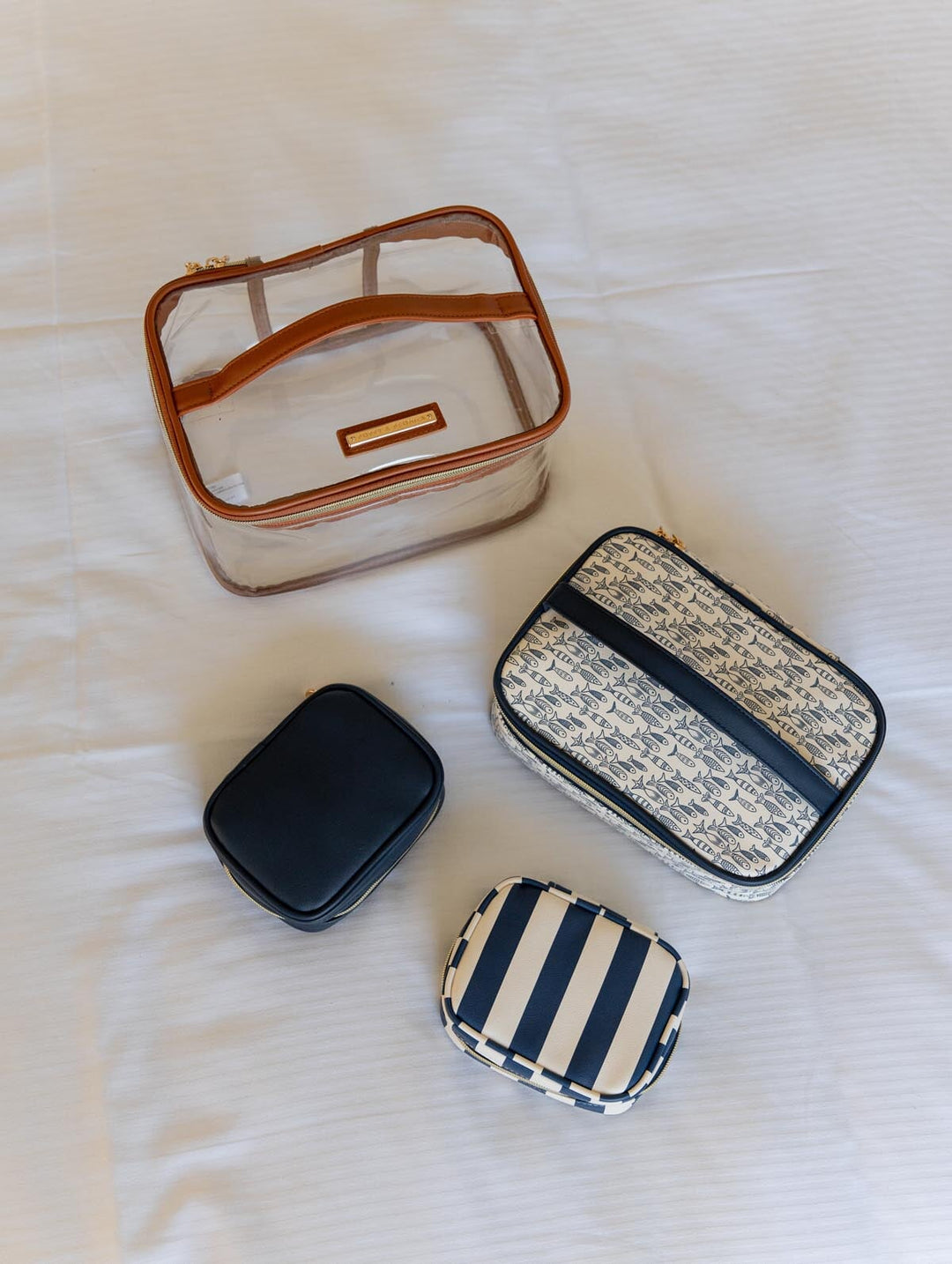 Four small cosmetic pouches on a white textured surface