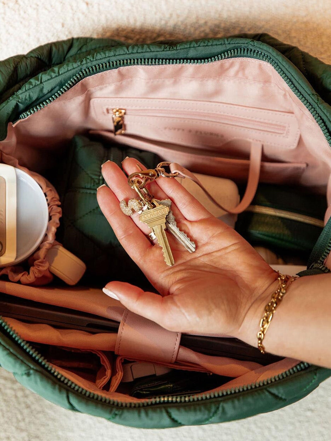 Hand holding keys with a green bag in the background