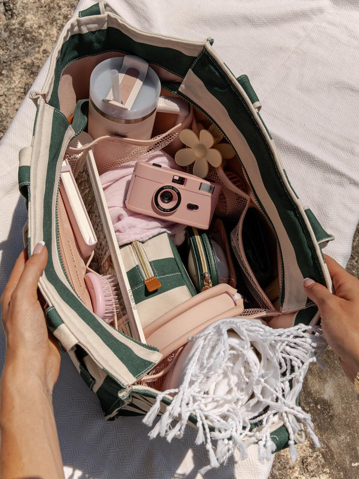 Open tote bag with travel items including a camera, toiletries, and clothing.