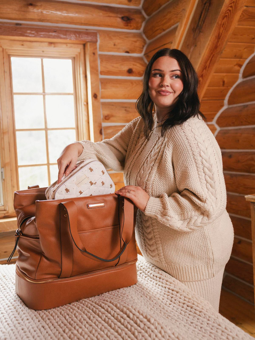 Woman in a cozy setting placing a makeup bag into a vegan leather travel bag
