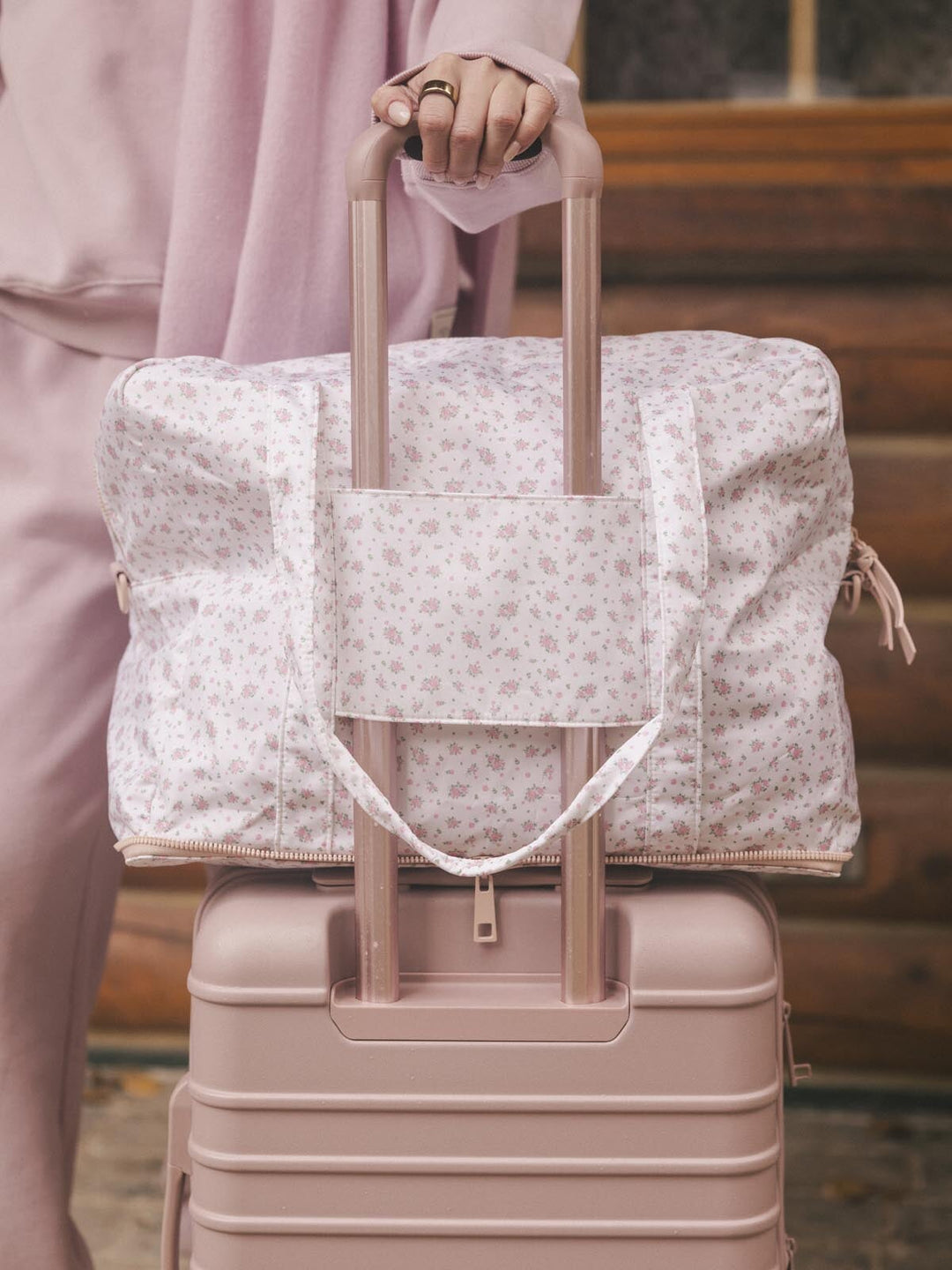 Floral-patterned duffel bag with a trolley sleeve on a suitcase