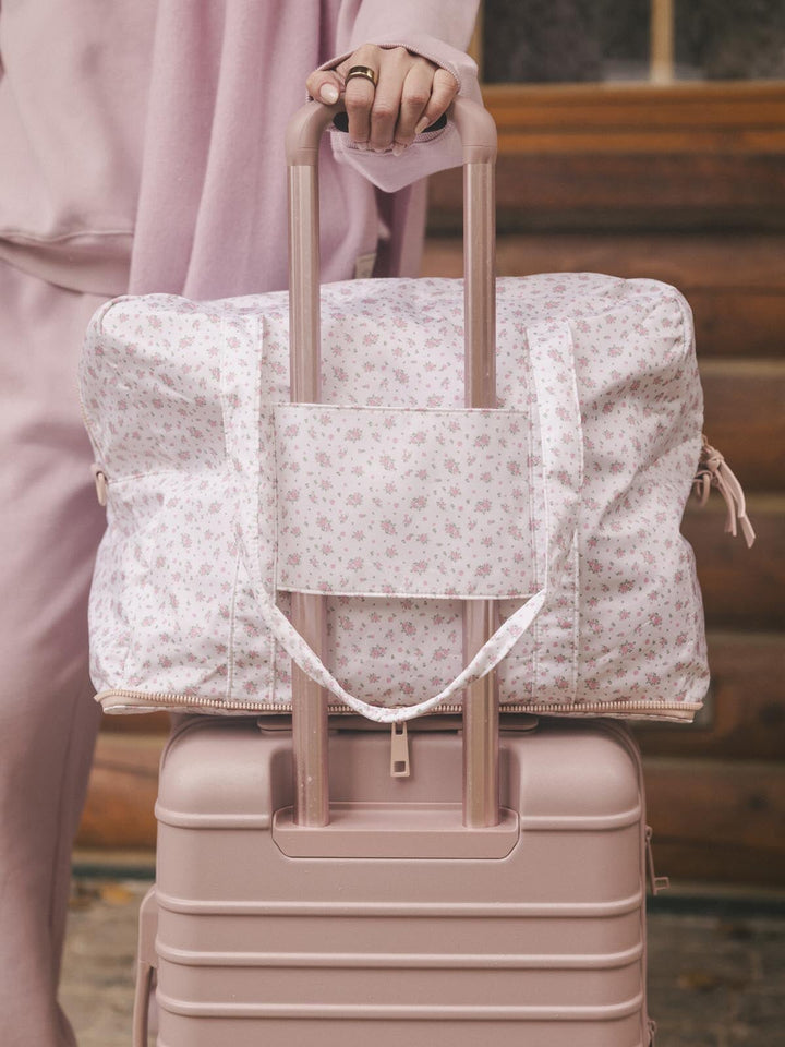 Floral-patterned duffel bag with a trolley sleeve on a suitcase