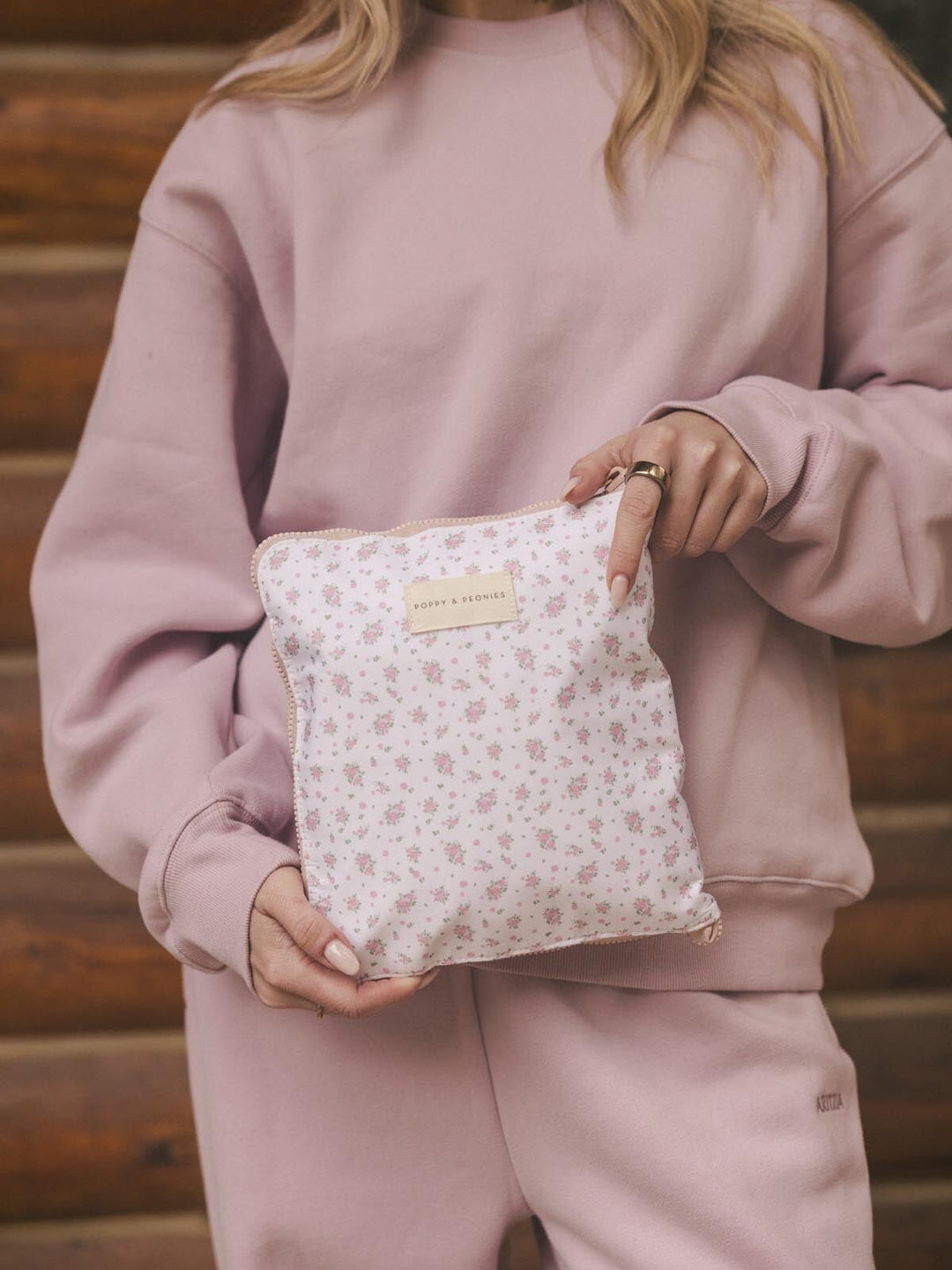 Person holding a floral-patterned pouch containing a packable duffel bag