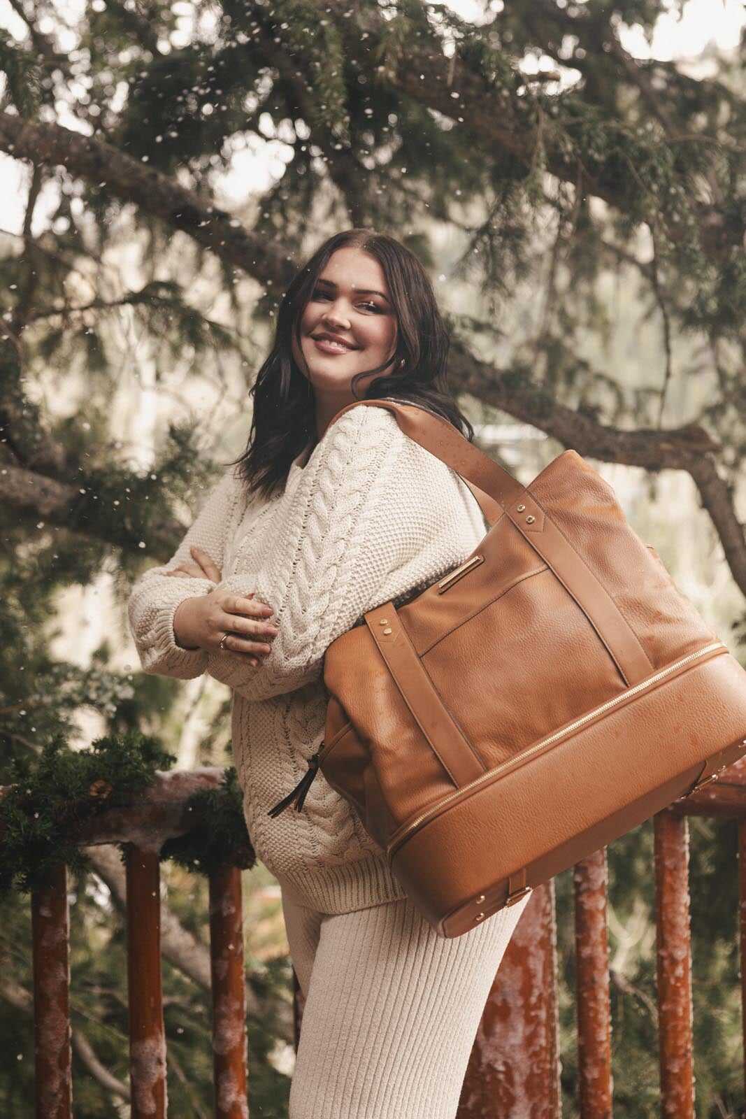Woman holding a brown vegan leather bag in a forest setting