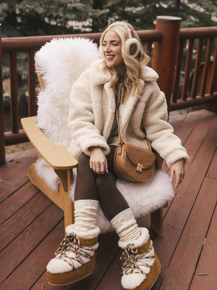 Woman in a fluffy white coat wearing a brown faux fur crossbody bag with a vegan leather strap