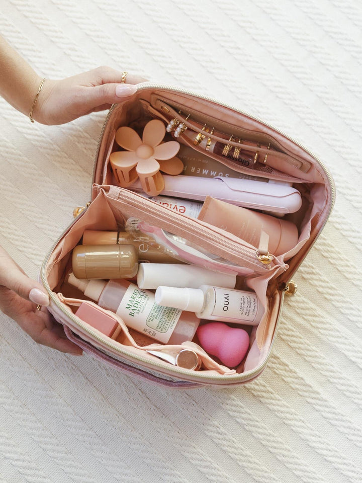 Pink cosmetic bag full of beauty products on a light background