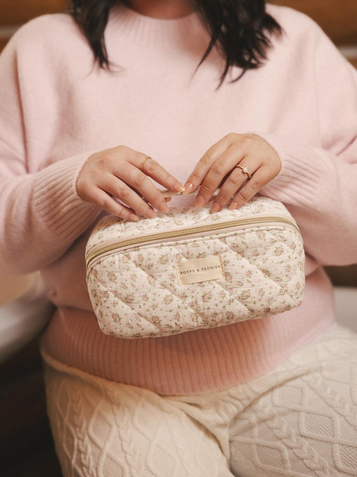 Woman holding a floral patterned cosmetic case 