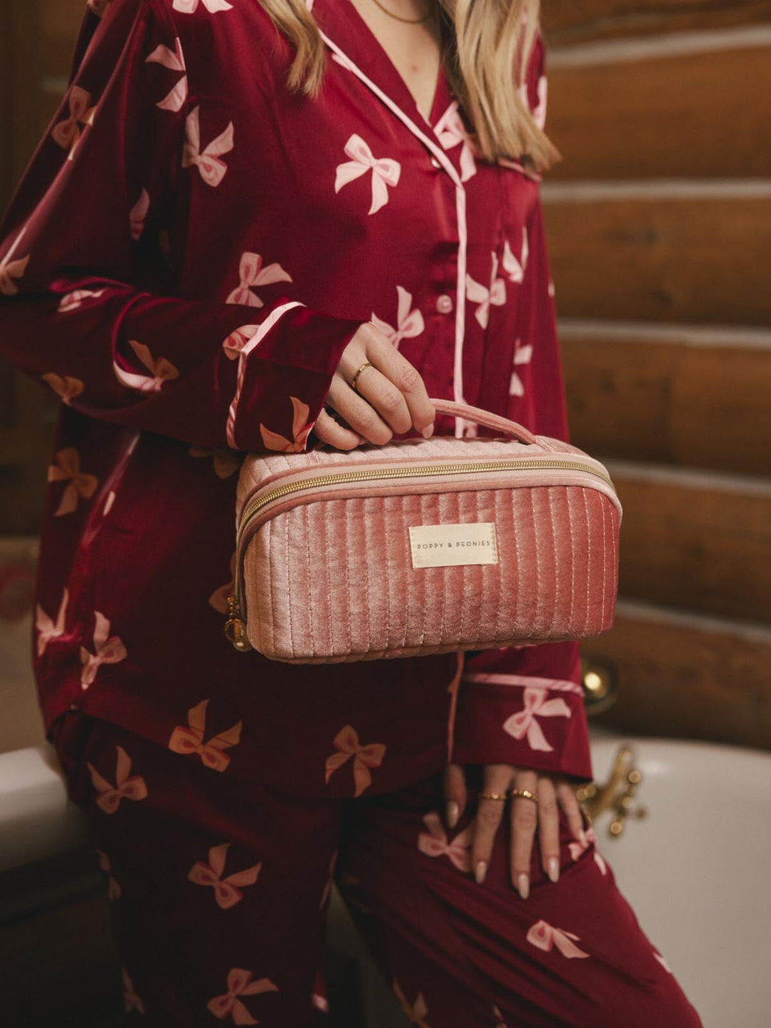 Woman holding a pink velvet quilted cosmetic bag with a handle