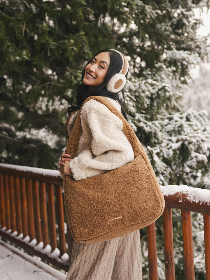 Person wearing a brown faux fur bag in a snowy outdoor setting