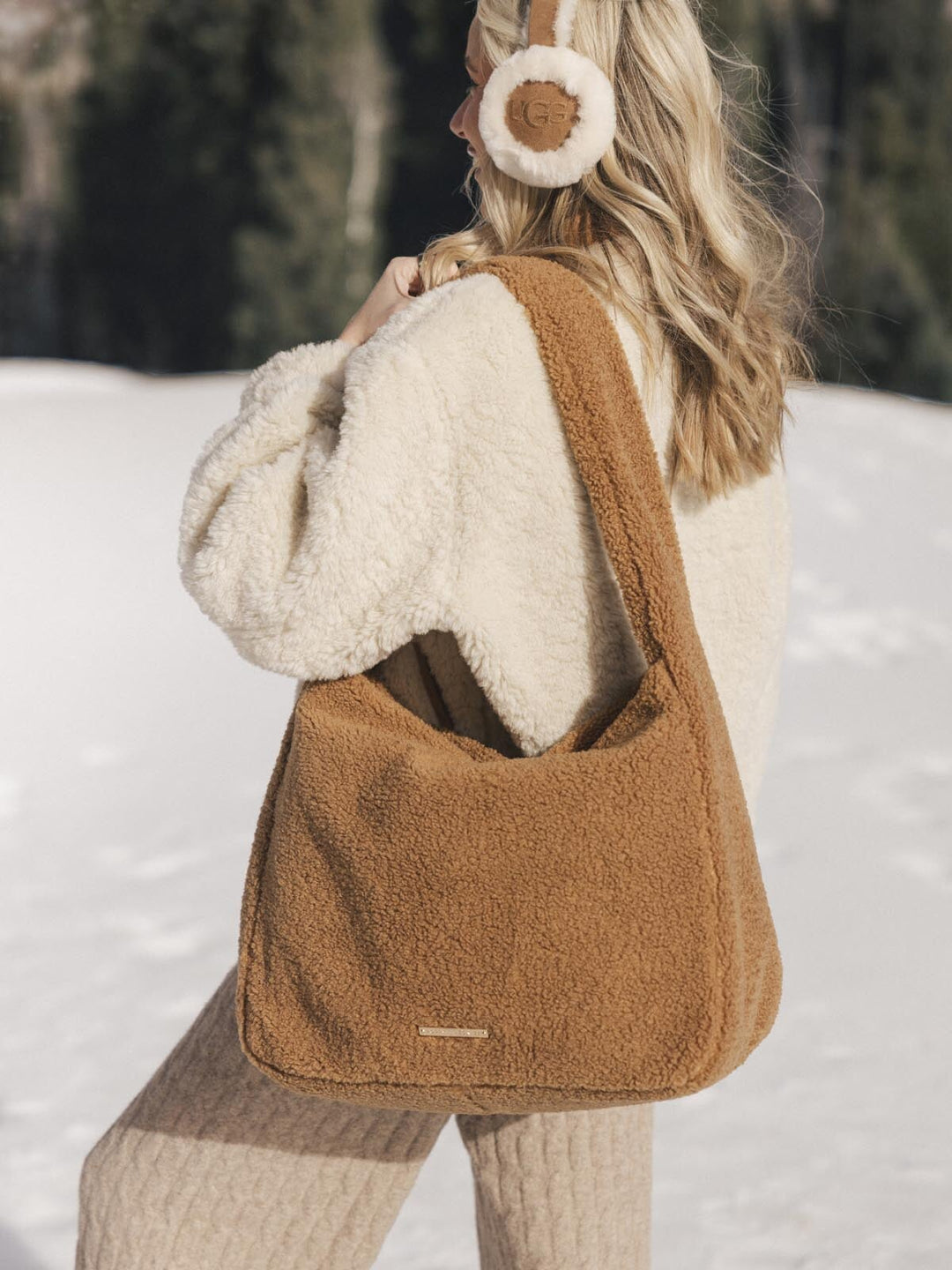 Person wearing a brown faux fur bag in a snowy landscape