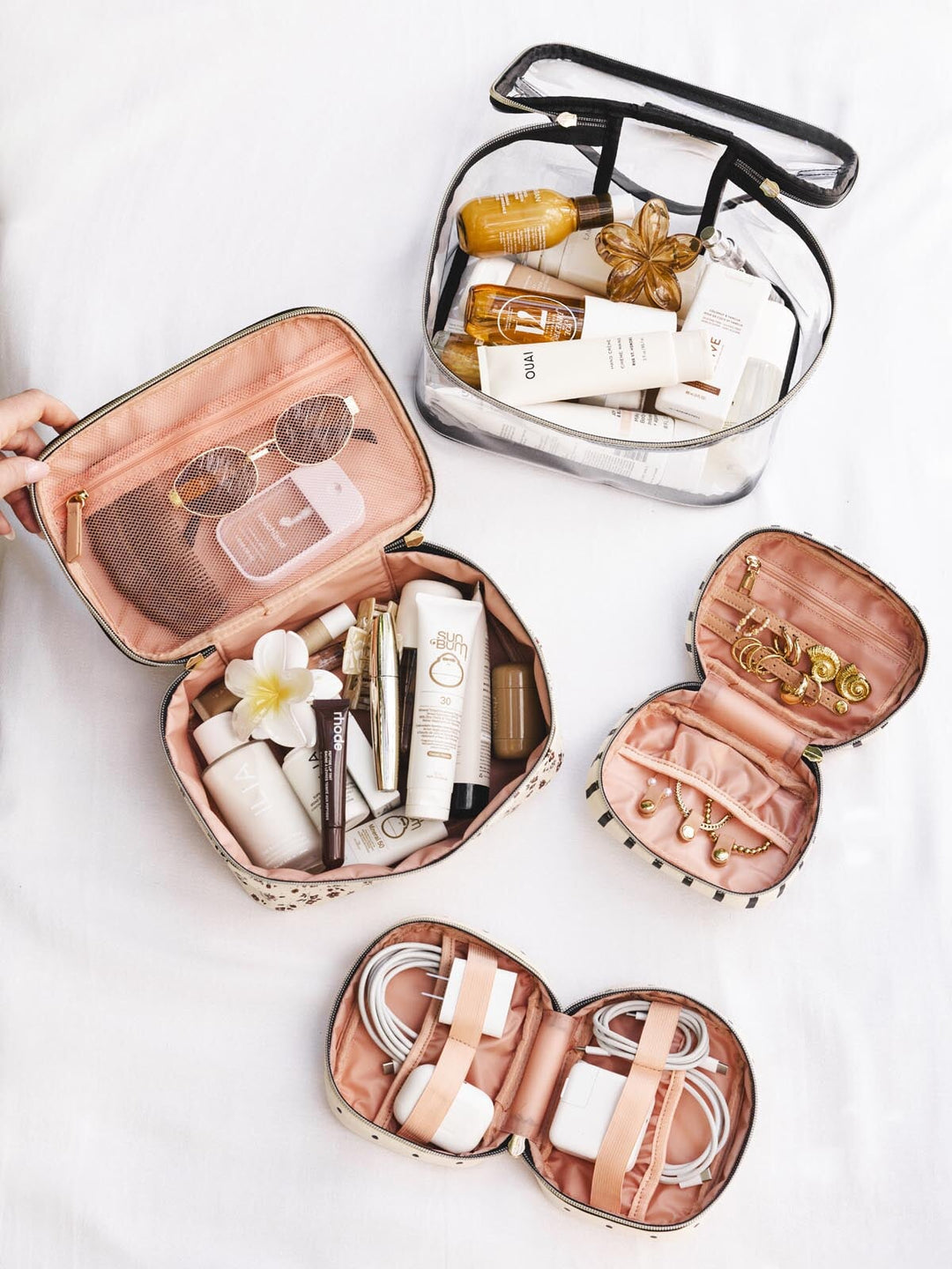 Set of travel-sized bags with skincare products and jewelry on a white background.