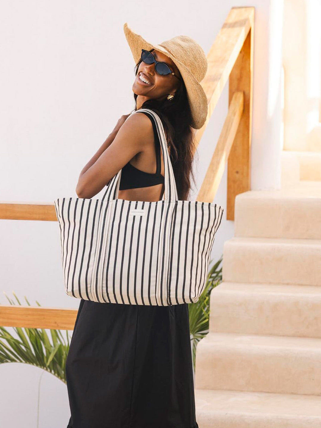 Woman with a striped tote bag standing on a staircase