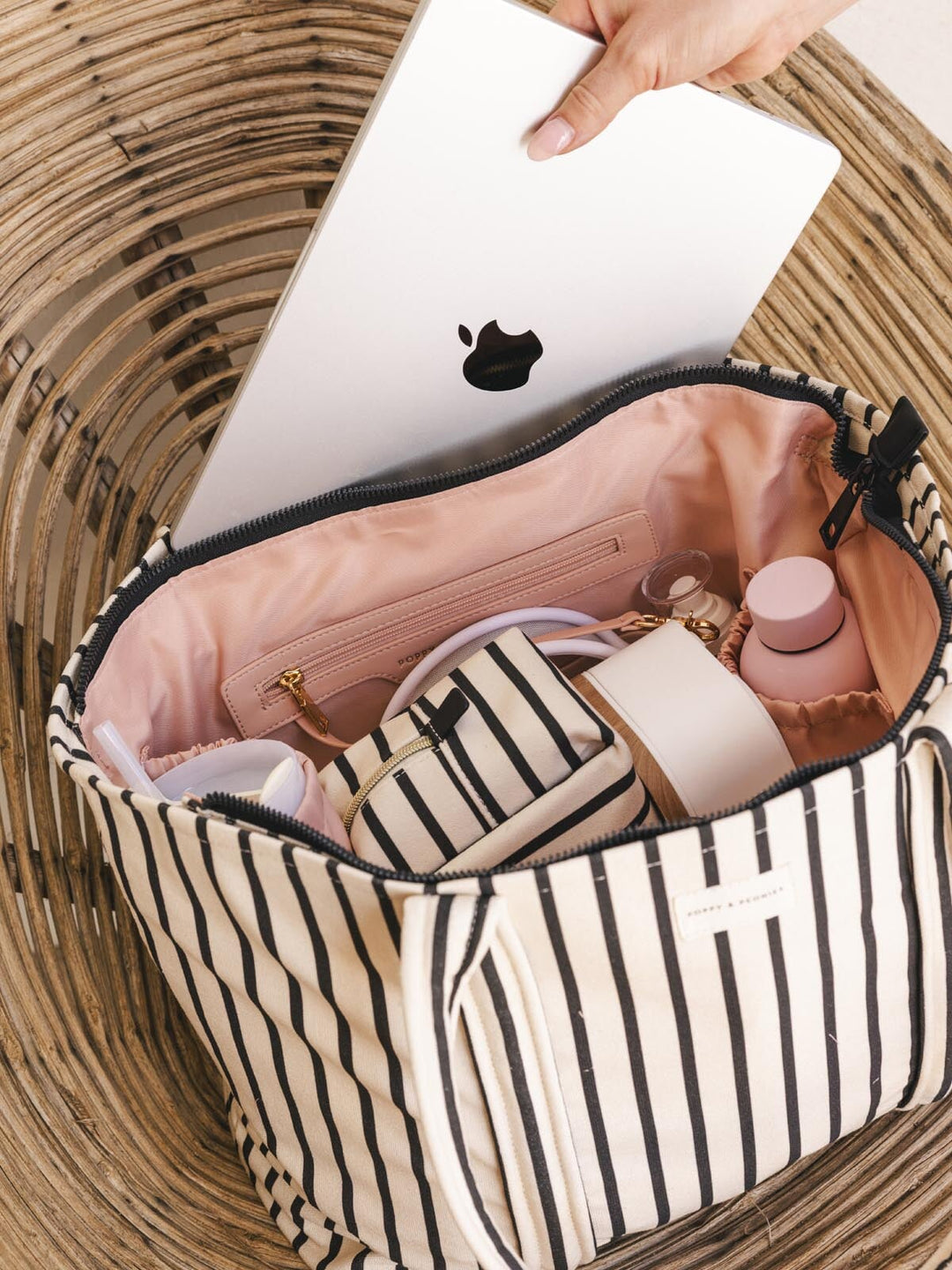 Hand placing laptop into striped tote bag
