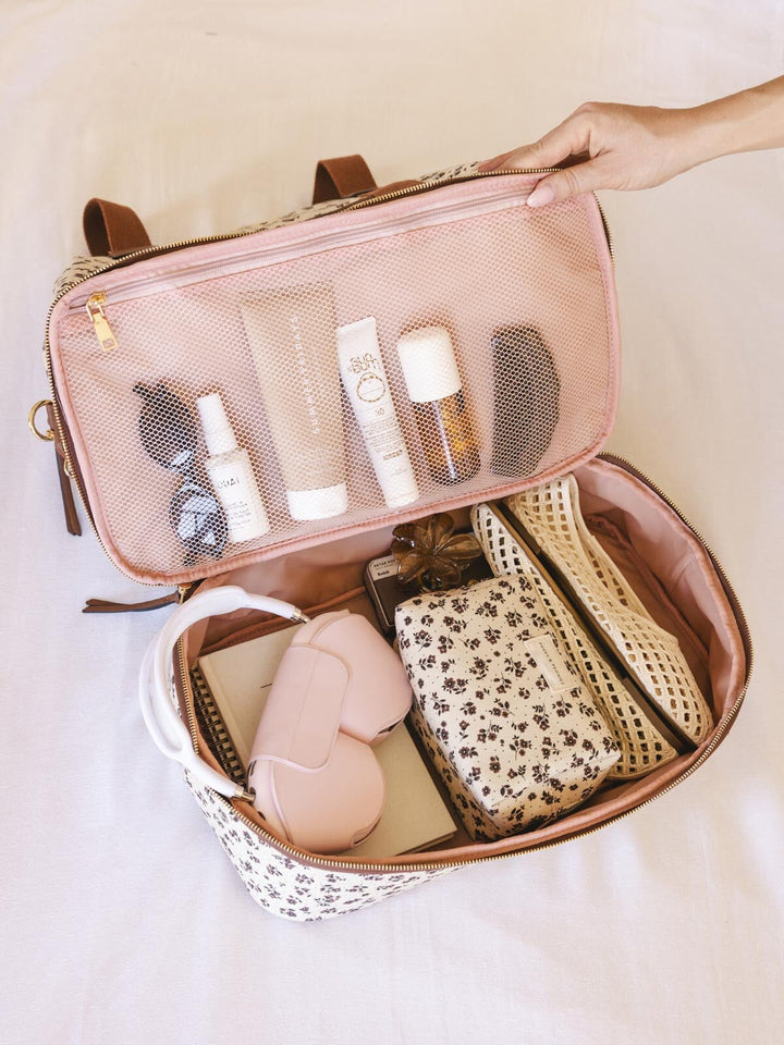 Interior bottom pocket of a floral-patterned travel bag with brown straps