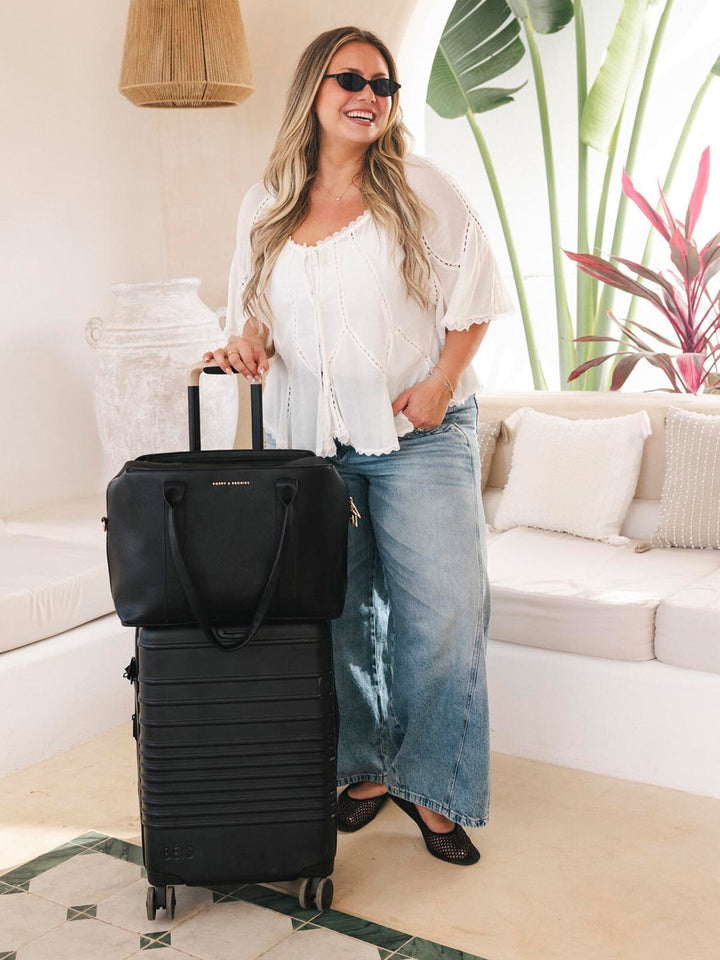 Woman with a black suitcase and handbag in a living room setting