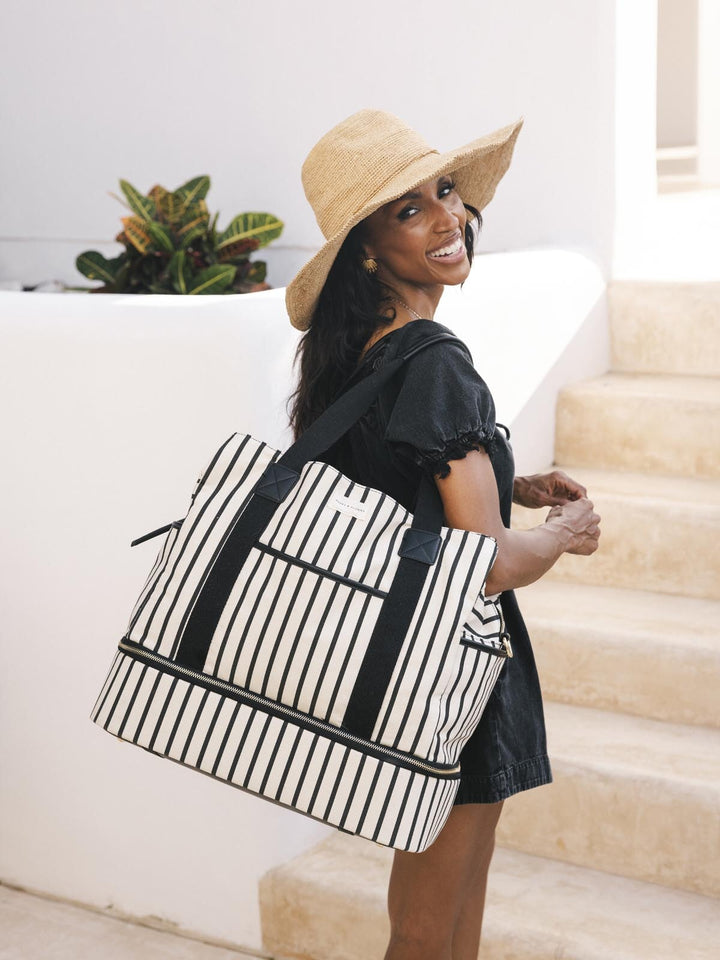 Woman holding a black and white striped bag on a staircase