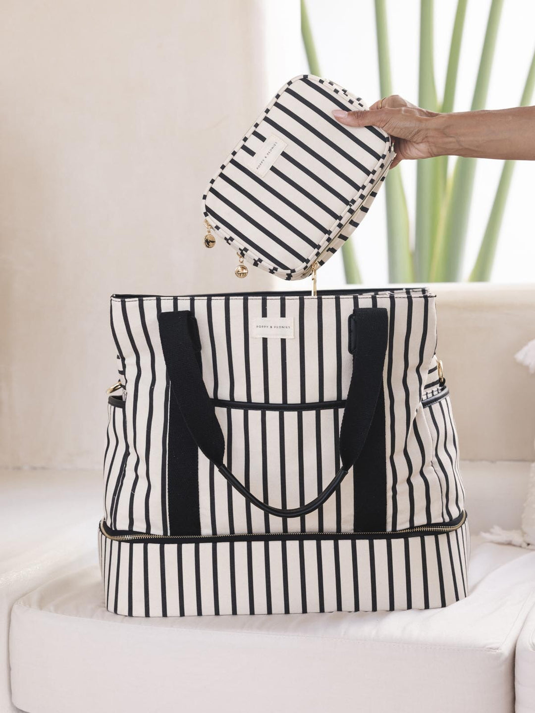 Hand placing a striped cosmetic bag into a matching travel bag