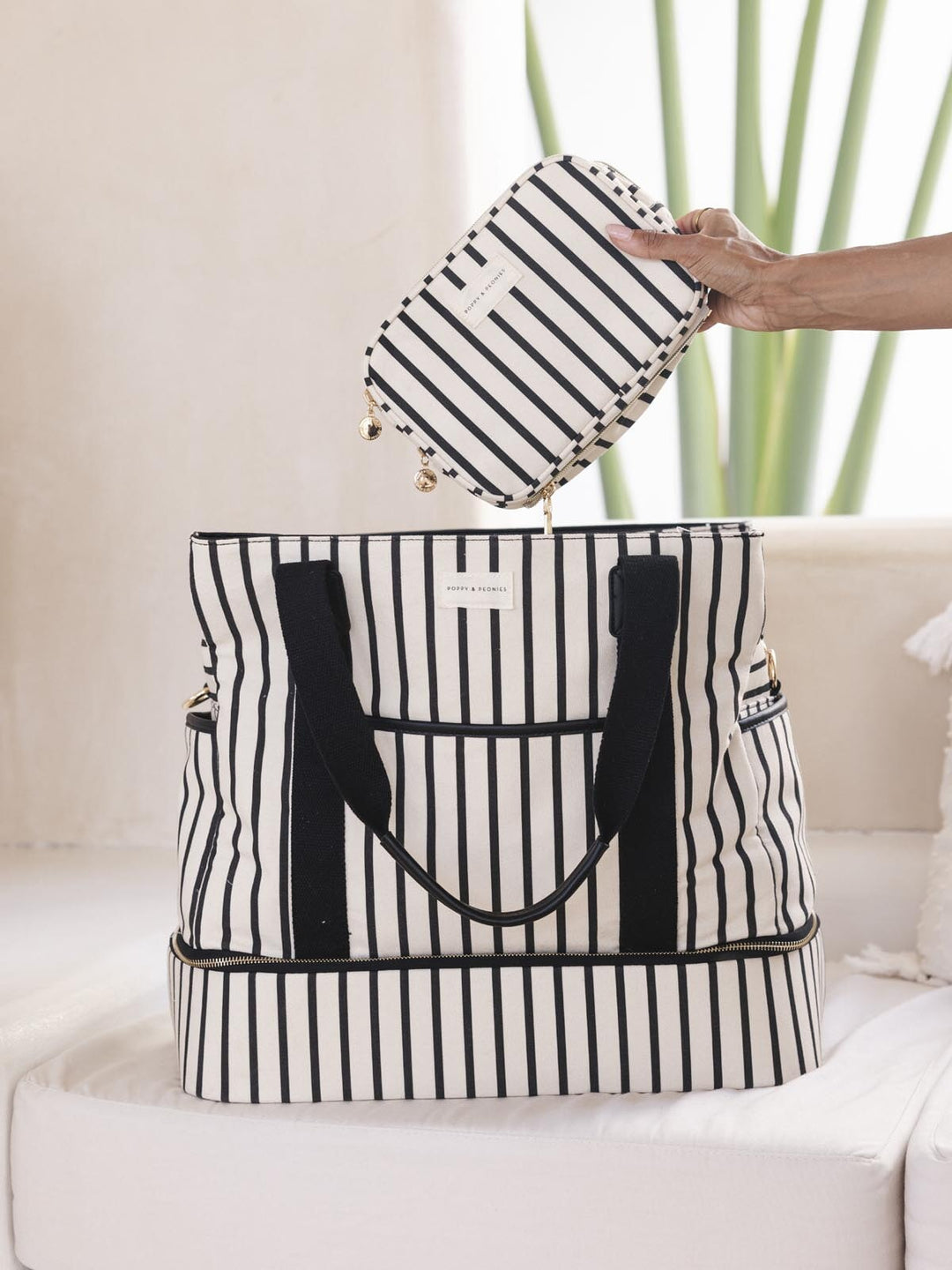 Black and white striped travel bag with matching pouch on a light background