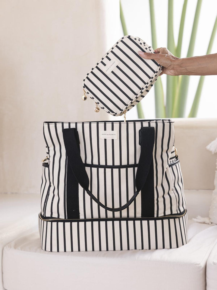 Black and white striped travel bag with matching pouch on a light background