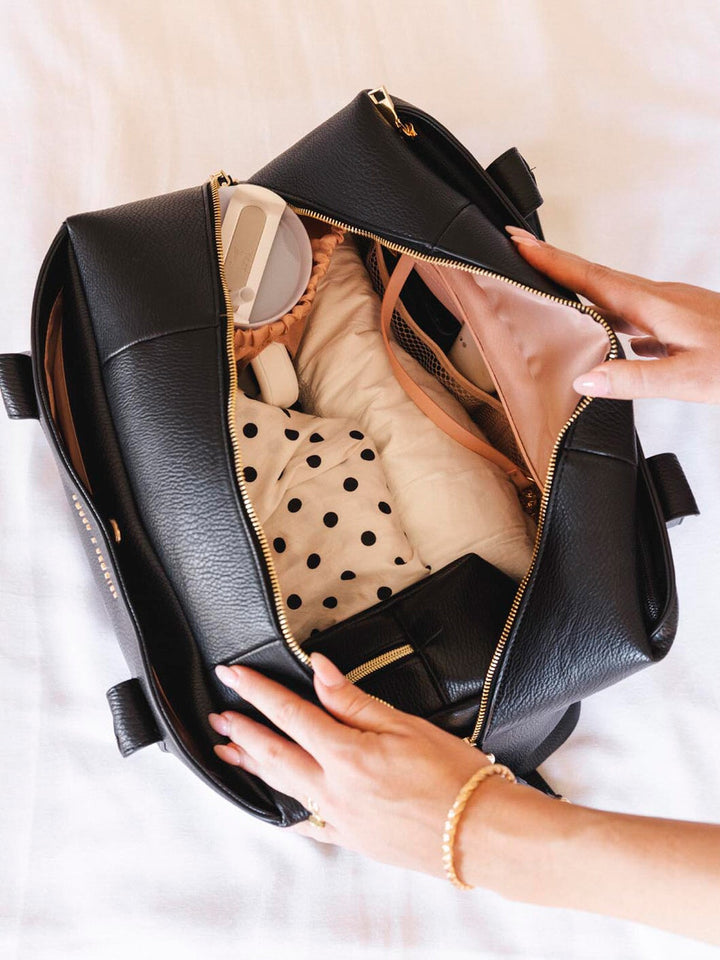 Open black duffle bag with a hand reaching inside, showing a neatly packed interior