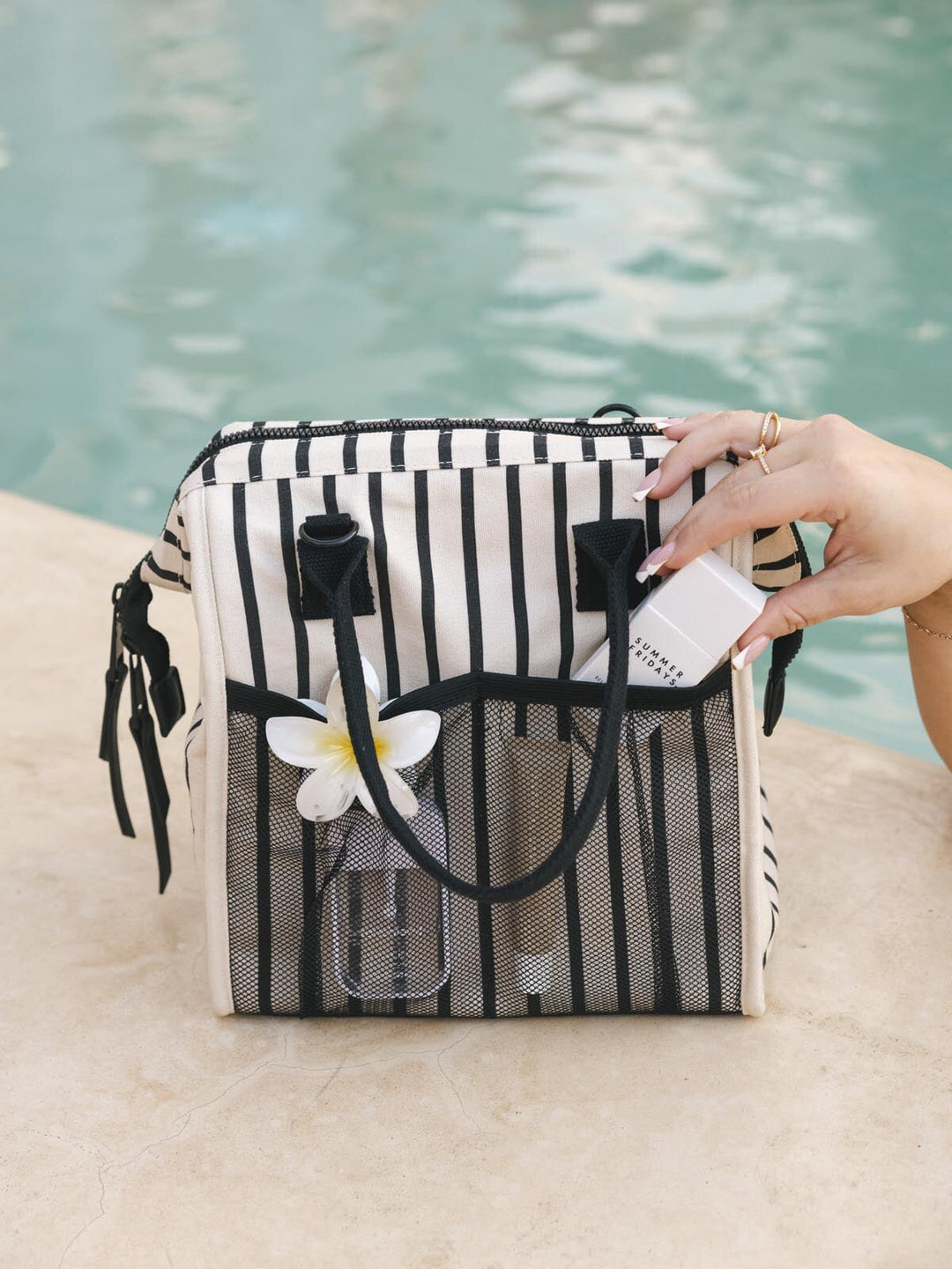 Black and white striped lunch bag by a pool.