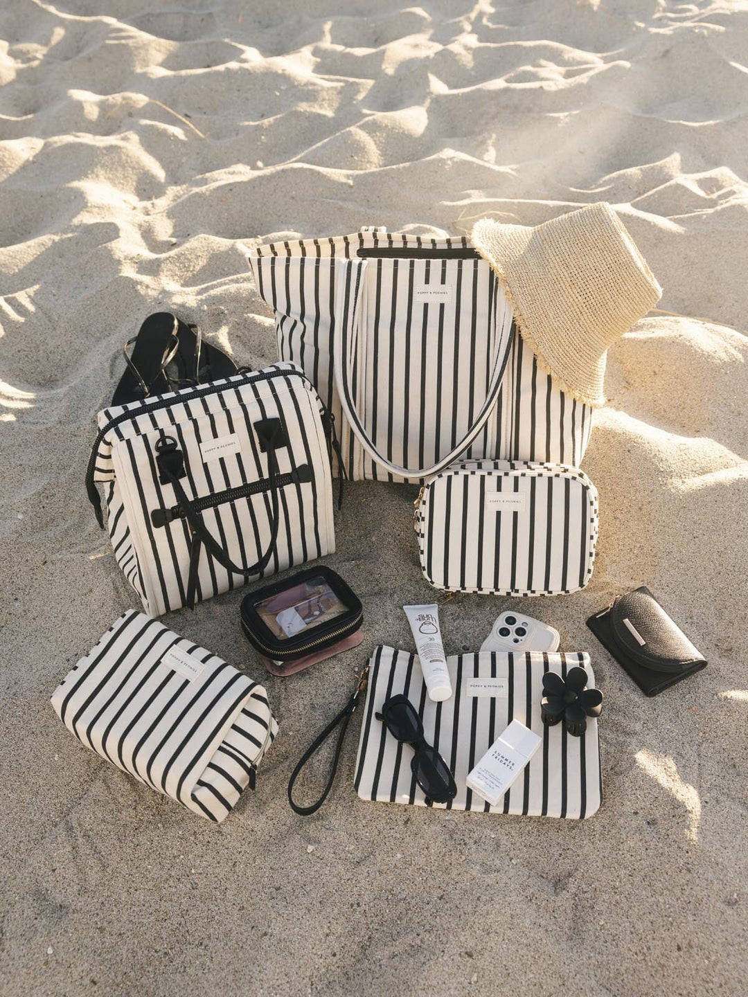 Black and white striped bags and pouches on a sandy surface
