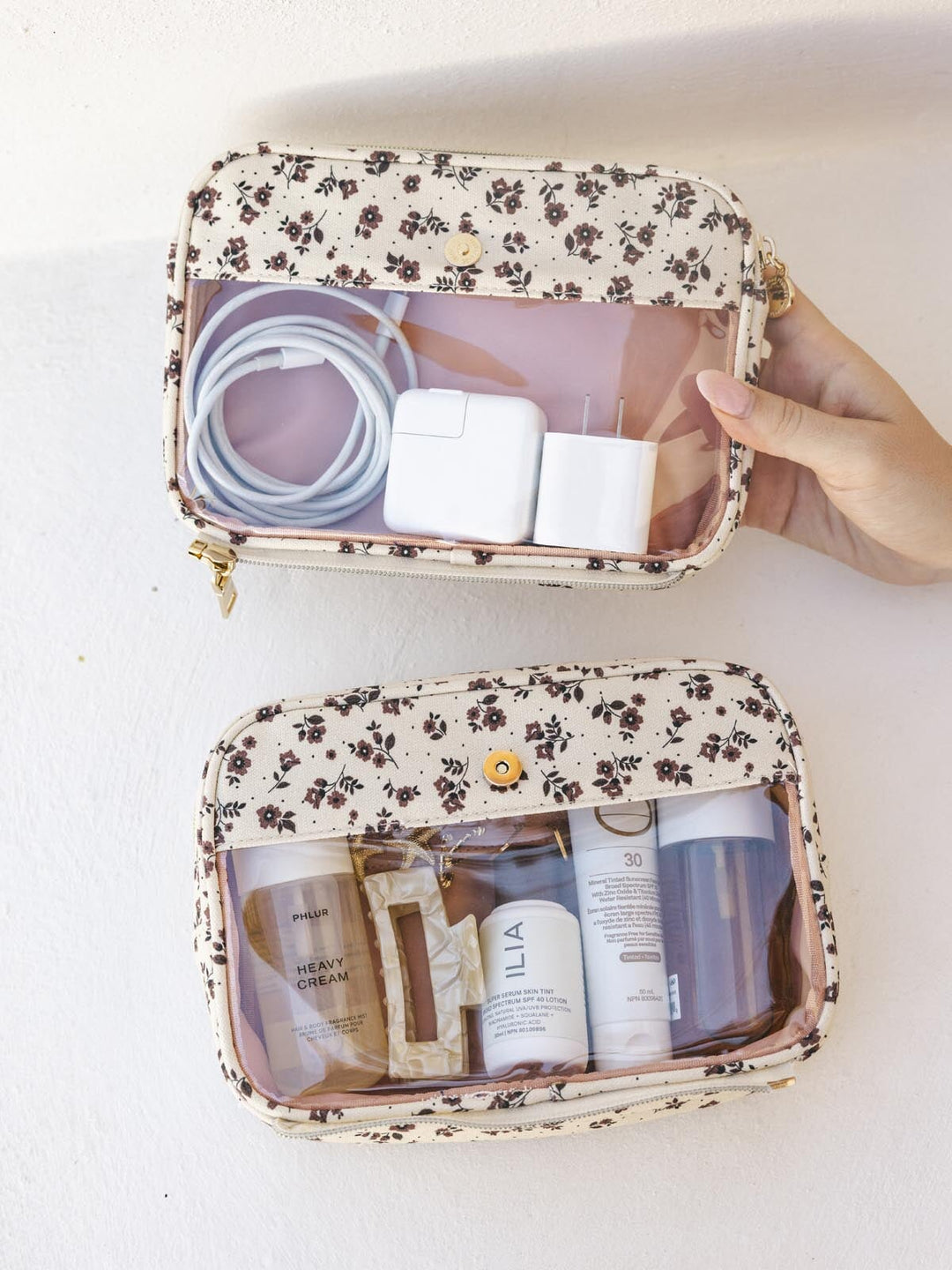 Floral-patterned travel pouches that split apart containing electronic accessories and skincare products on a white background.