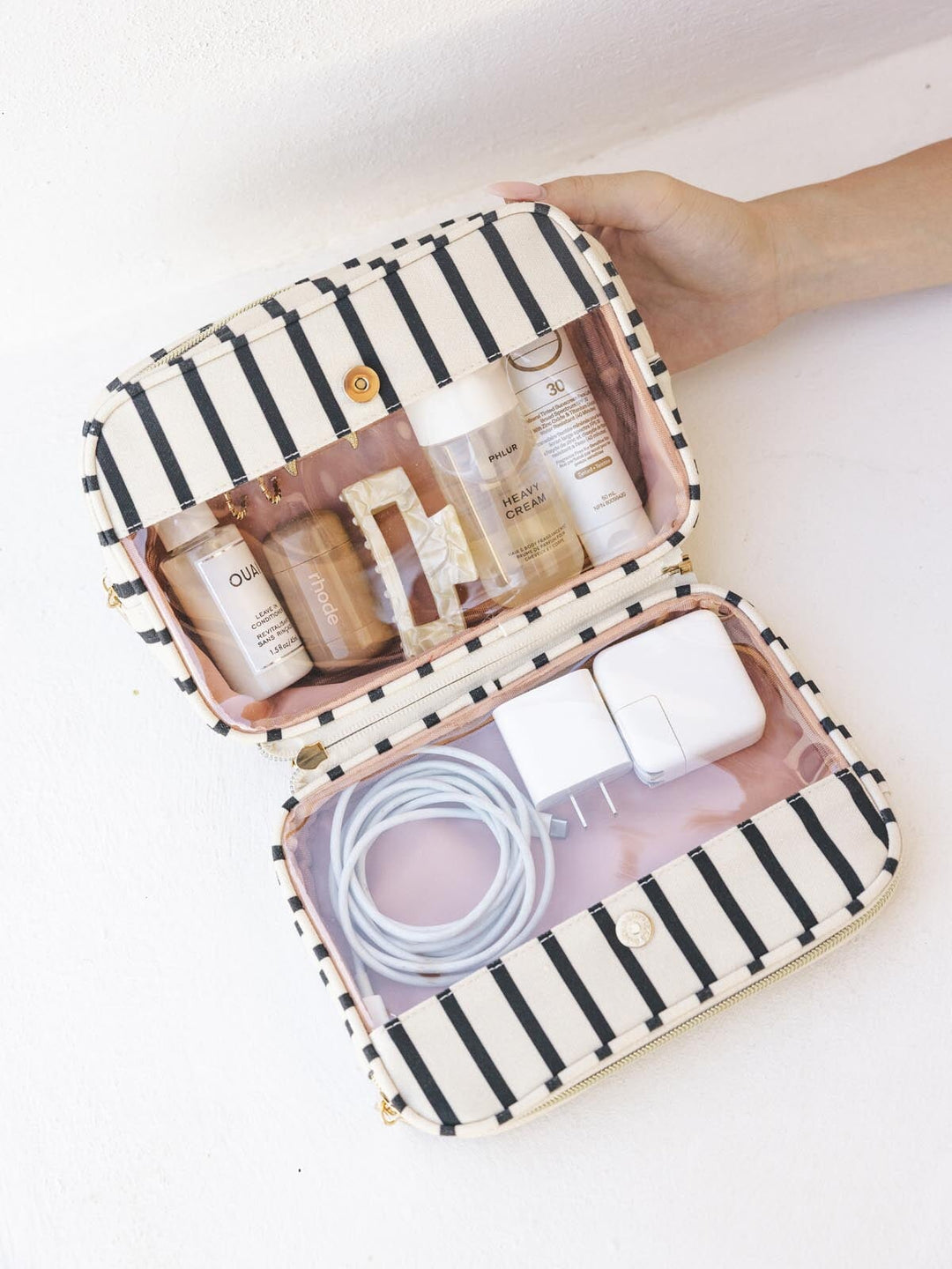 Striped travel case with skincare products and charging cables.
