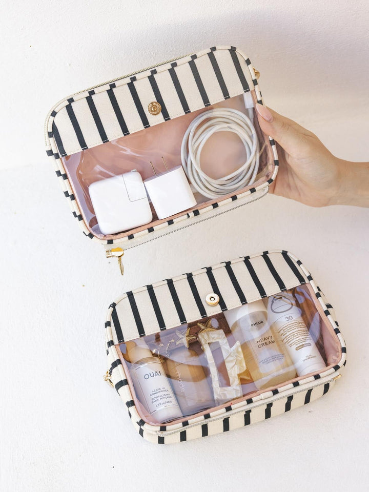 Black and white striped travel pouches with skincare products on a white background