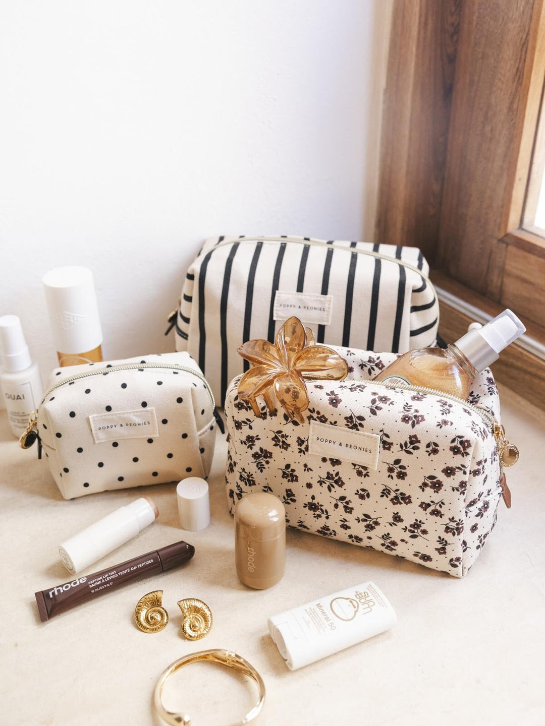 Set of three cosmetic bags and products on a light surface with a neutral background