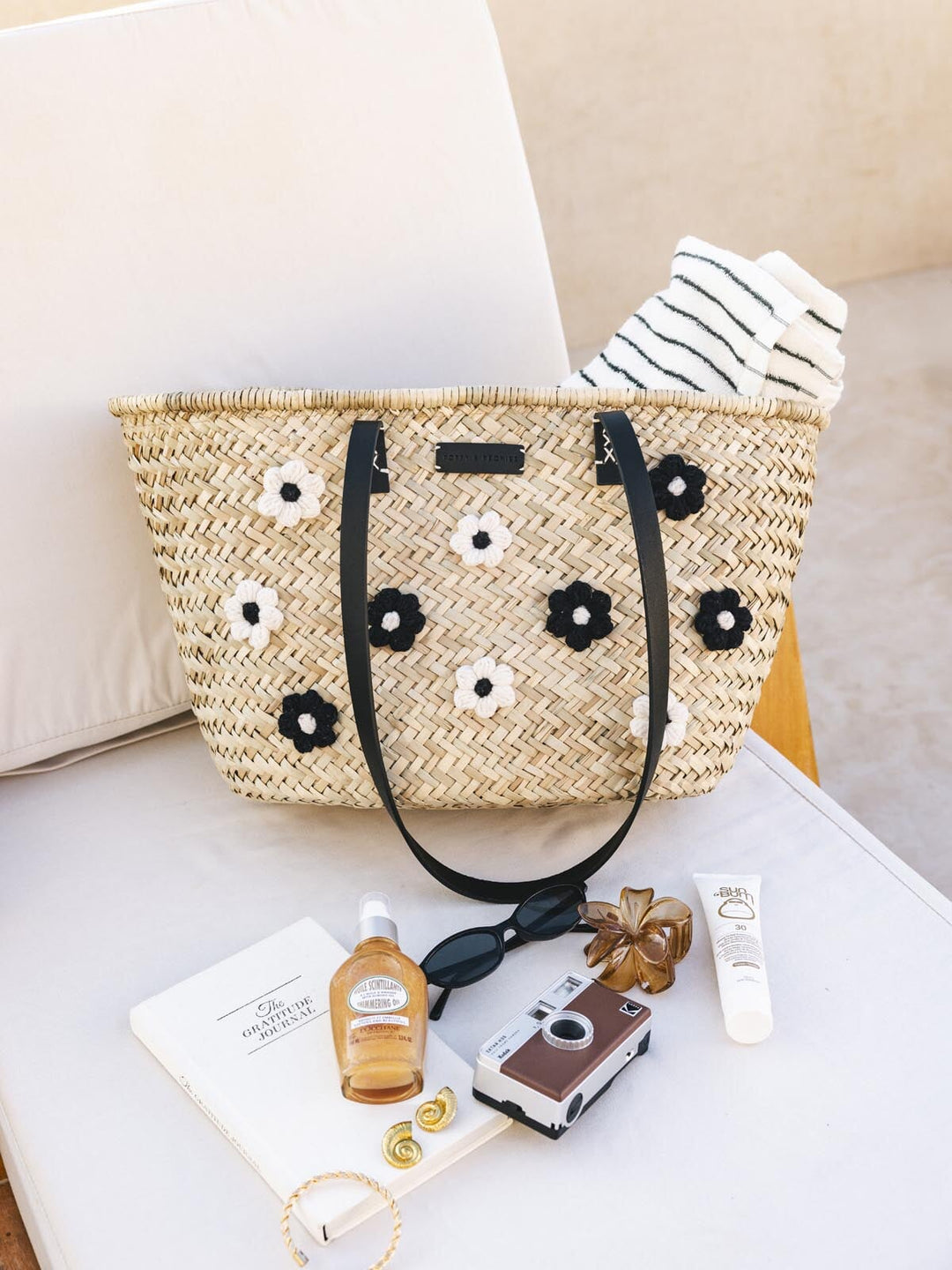 Woven straw bag with floral patterns on a beach chair.