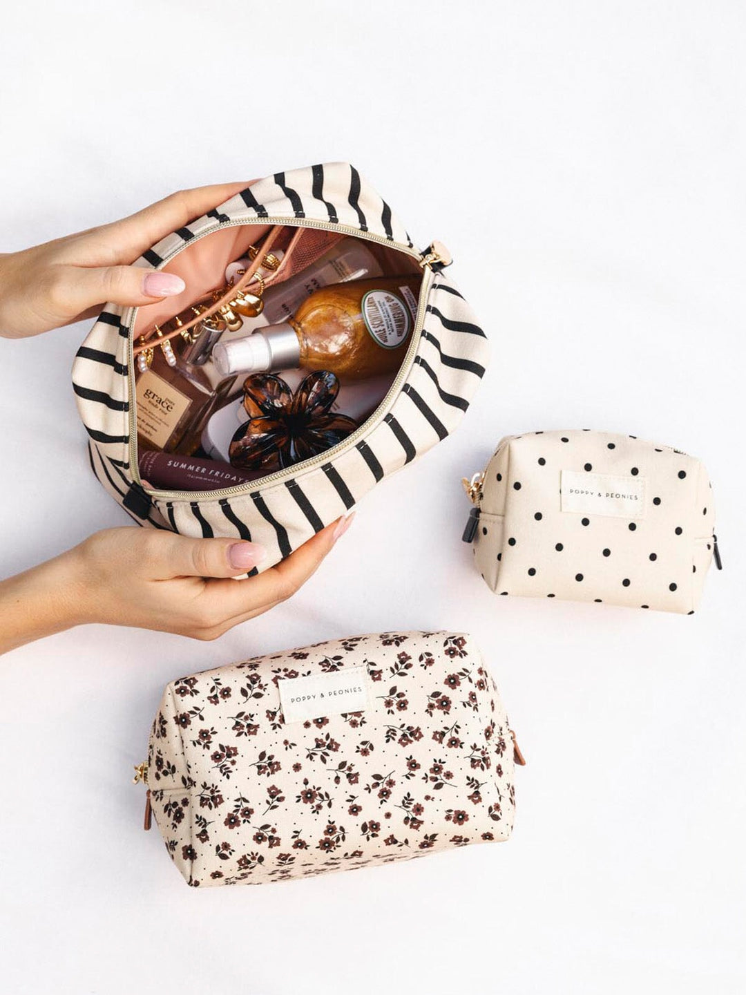 Three cosmetic bags with a polka dot pattern, floral pattern and stripe patterns. 