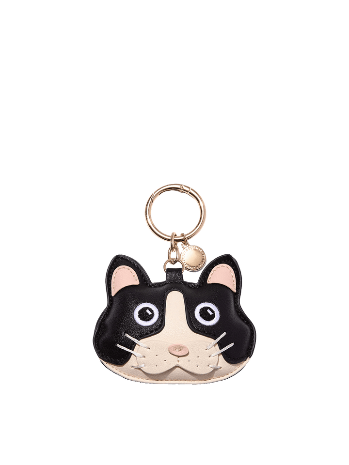 Poppy and Peonies Cat Bag Charm featuring a playful black and cream cat face design with pink inner ears, wide embroidered eyes, a pink nose, white whiskers, and gold-tone keyring hardware with a small round branded charm.