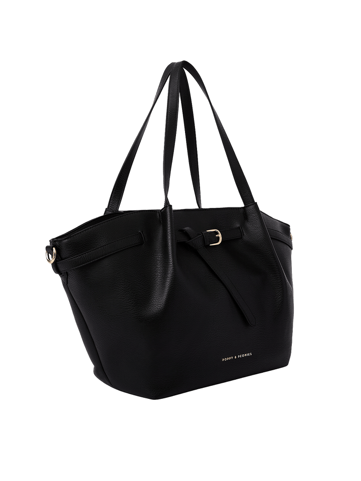 Poppy & Peonies The Knot Tote in Black, shown from a three-quarter angle highlighting its roomy trapezoid shape, decorative belted detail, long shoulder handles, and gold-tone hardware.