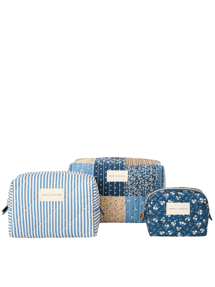 Clean product shot of the Poppy & Peonies Cosmetic Trio in Navy Patchwork, featuring all three coordinating cosmetic cases together: a blue-and-white striped case, a navy patchwork case, and a navy floral case.