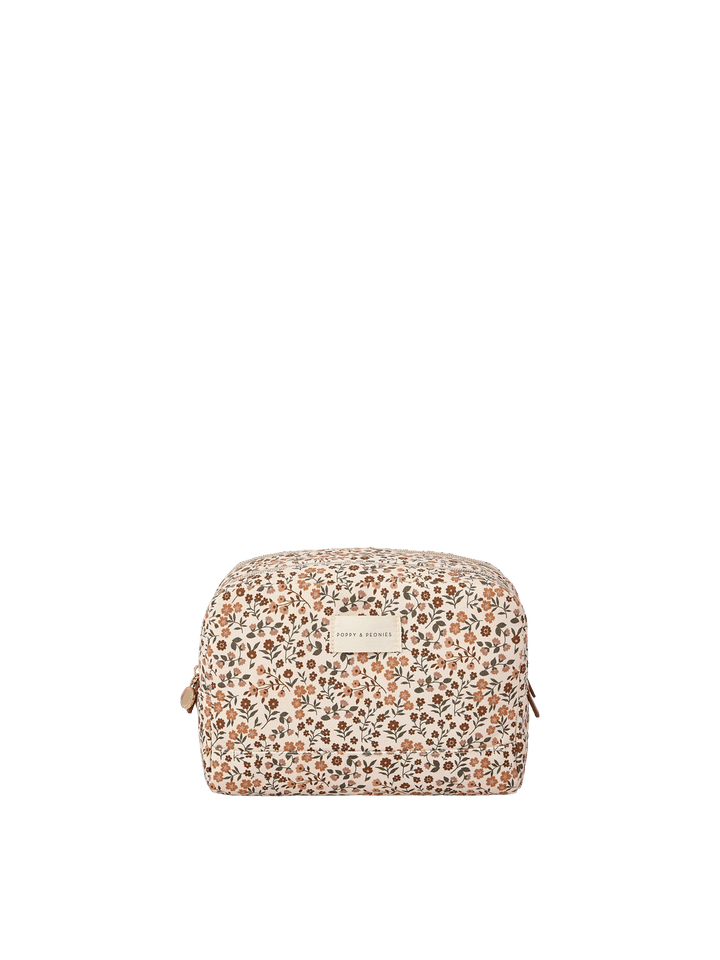 Poppy and Peonies Double Take Cosmetic Case October Floral featuring a cream-colored pouch with a delicate all-over floral print in warm brown, rust, and muted orange tones, a rounded rectangular shape, zippered closure, and a branded front label.