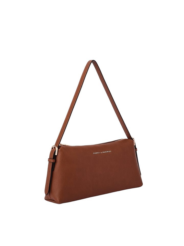 Poppy & Peonies The Soho Shoulder Bag in Chestnut, shown from a three-quarter angle highlighting its slim profile, adjustable shoulder strap with buckle details, gold-tone hardware, and pebbled texture.
