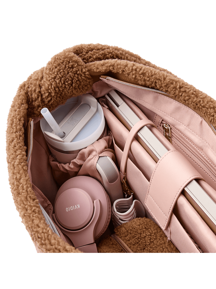 Pink headphones and water tumbler in a brown faux fur bag