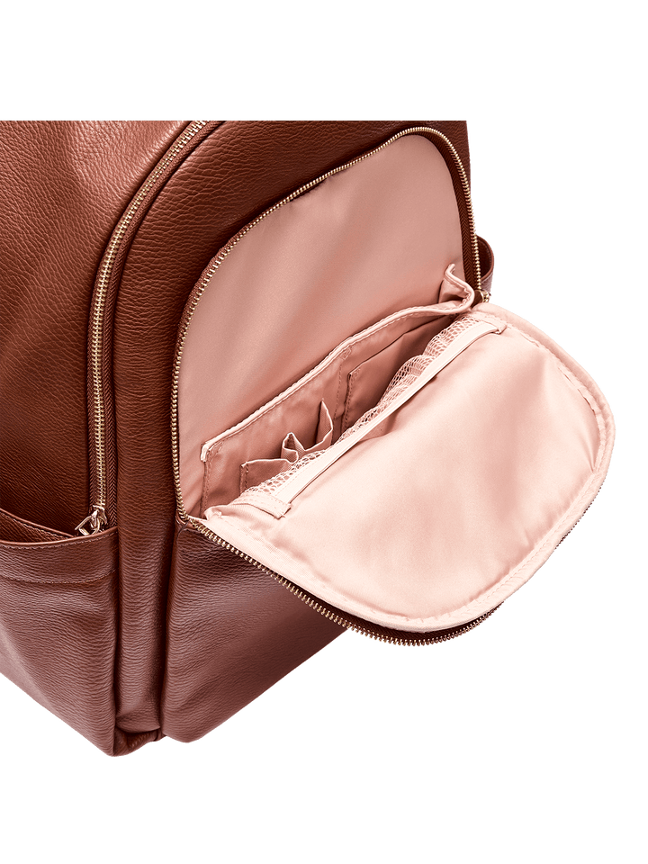 Brown leather backpack with open front pocket showing pink interior.