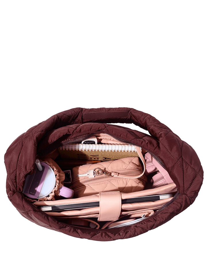 Brown quilted handbag with visible contents on a transparent background