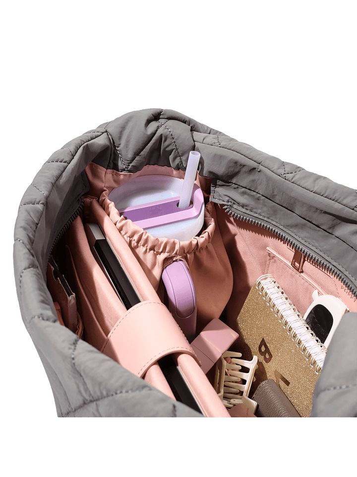 Quilted grey bag with a water bottle holder.