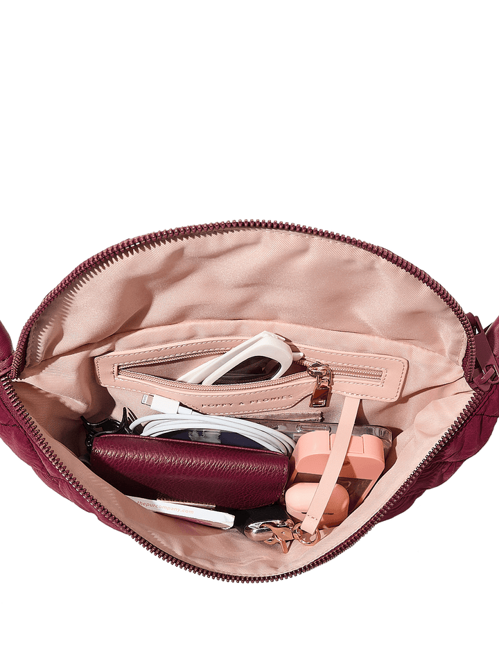 Open berry coloured handbag with various items on a transparent background