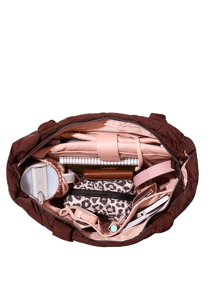 Open brown quilted bag with various items 