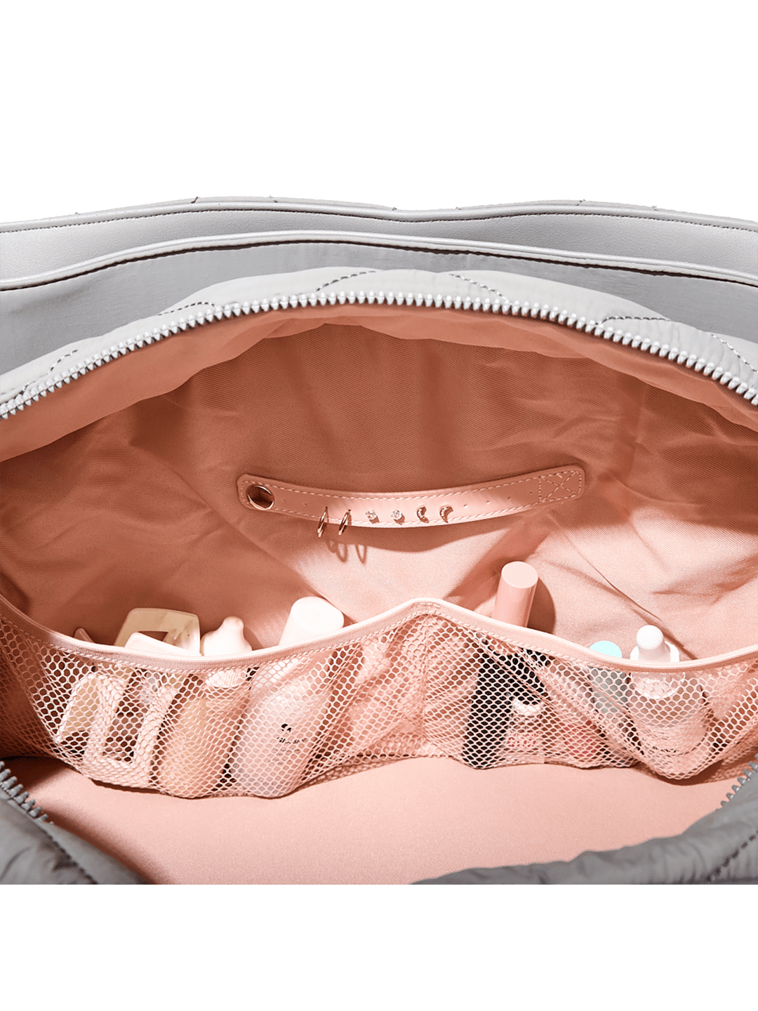 Grey bag with pink mesh pocket and white items inside on a green background