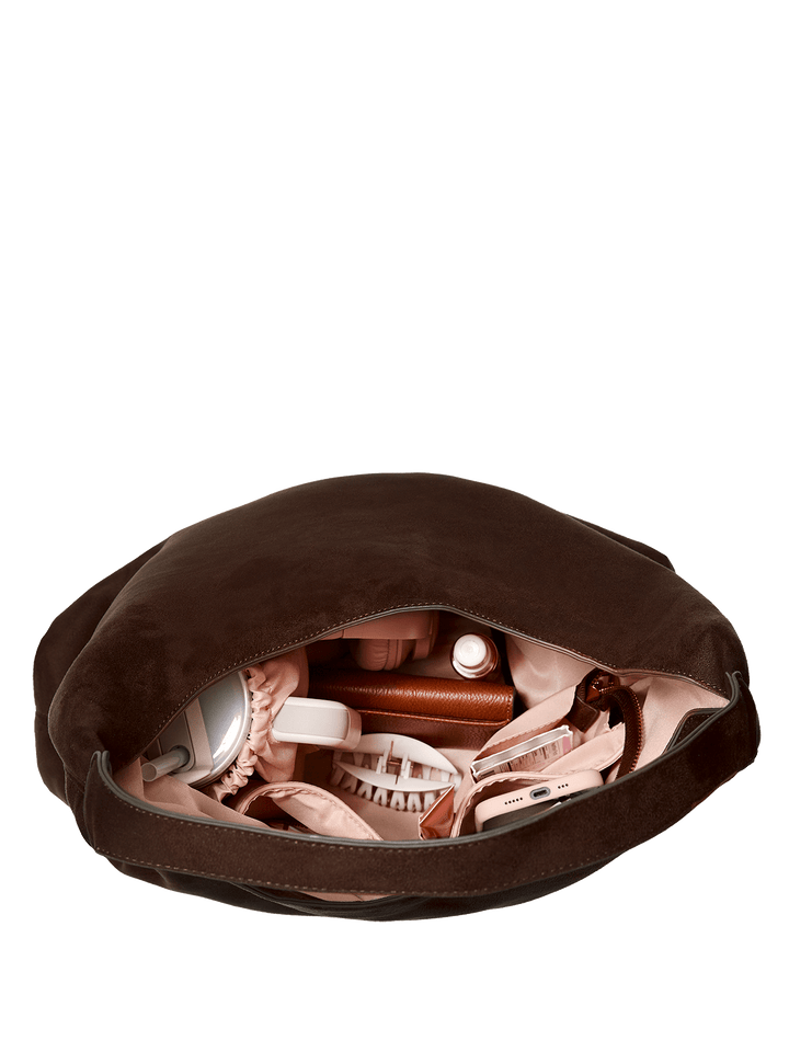 Brown vegan suede bag with makeup items on a transparent background