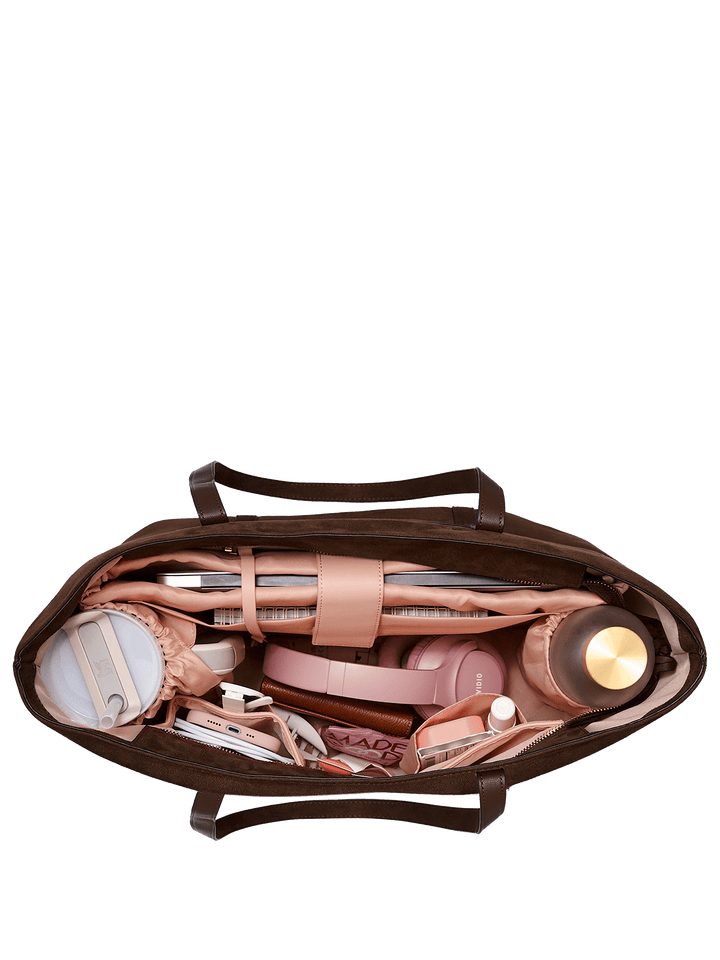 Open brown leather bag with various items on a transparent background