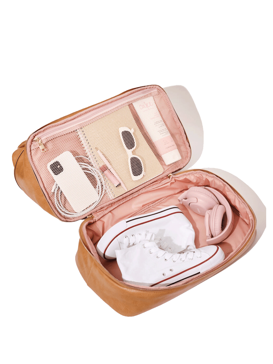 Open travel bag shoe organizer compartment with white sneakers and headphones in it.