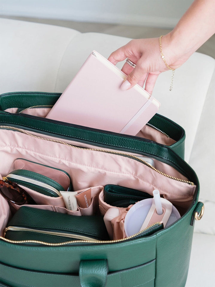 Notebook being placed into the organized interior of the Poppy & Peonies Double Duty Tote in Heritage Green.