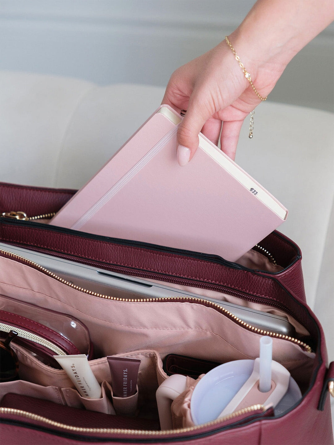 Notebook being placed into the organized interior of the Poppy & Peonies Double Duty Tote in Berry.
