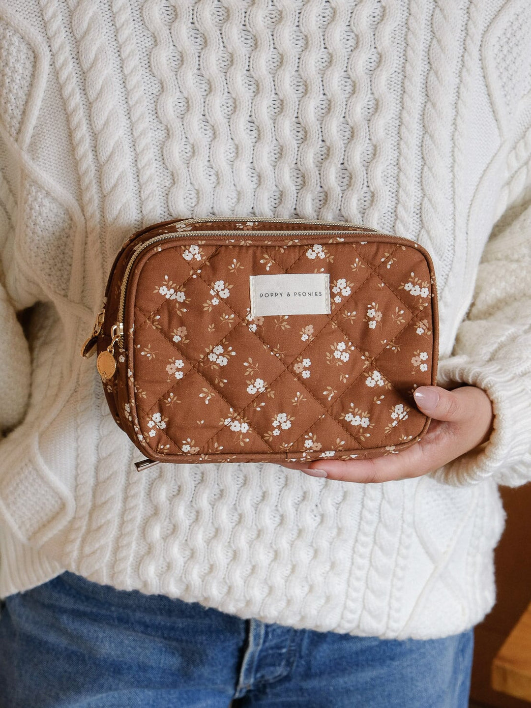 Lifestyle shot of the Poppy & Peonies Pretty Connected Case in Brown Floral held against the body to show its compact size and portability.